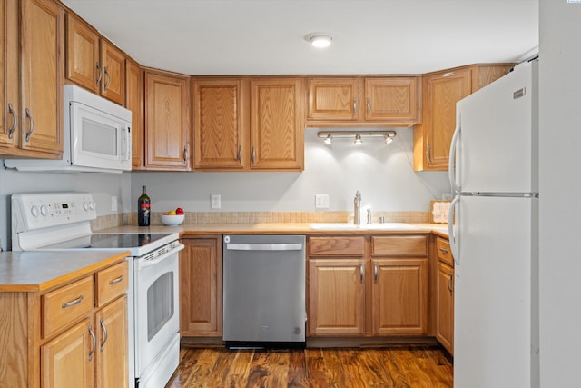 kitchen with white appliances, a sink, light countertops, dark wood-style floors, and brown cabinetry