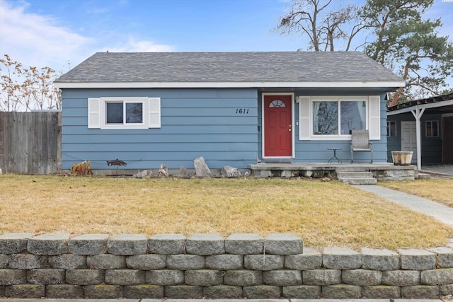 view of front of home featuring a front yard, roof with shingles, and fence