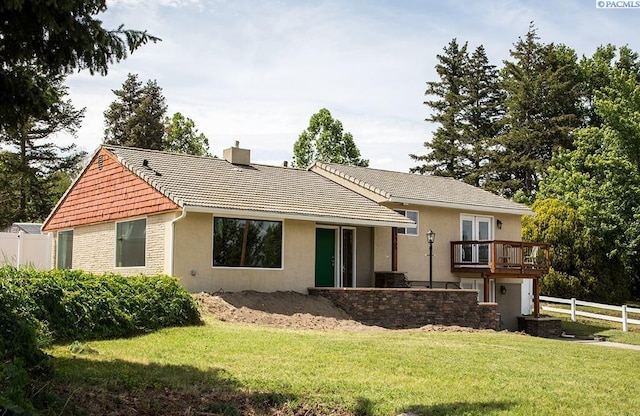 view of front of home featuring a tiled roof, stucco siding, a front yard, fence, and a chimney