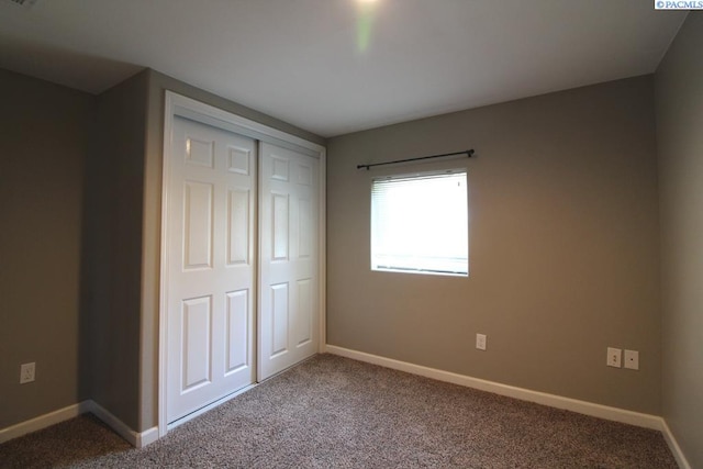 unfurnished bedroom with a closet, baseboards, and carpet flooring