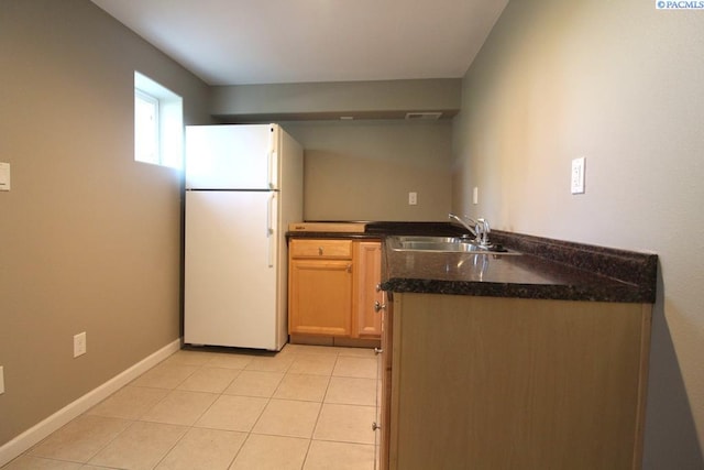 kitchen with light tile patterned floors, visible vents, a sink, freestanding refrigerator, and dark countertops