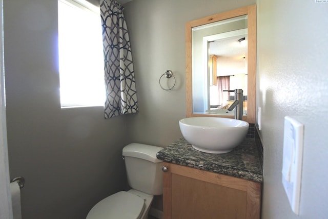 half bathroom featuring vanity, toilet, and a healthy amount of sunlight
