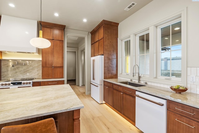 kitchen featuring pendant lighting, sink, white appliances, light hardwood / wood-style flooring, and tasteful backsplash