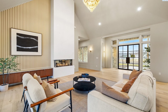 living room featuring an inviting chandelier, light hardwood / wood-style flooring, and high vaulted ceiling