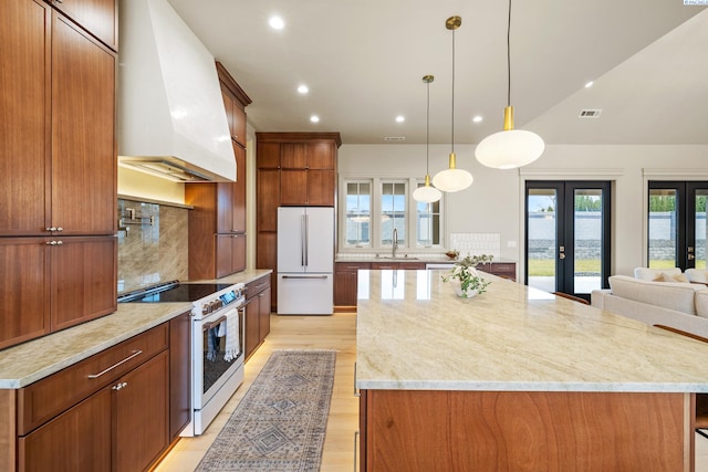 kitchen with a large island, sink, white appliances, premium range hood, and french doors