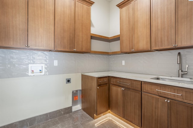 kitchen featuring tasteful backsplash, light stone countertops, and sink