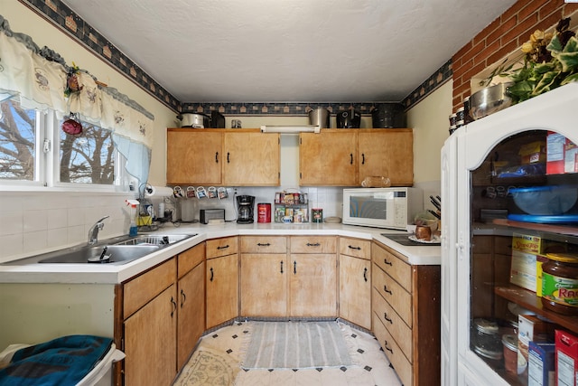 kitchen with decorative backsplash, light countertops, white microwave, and a sink