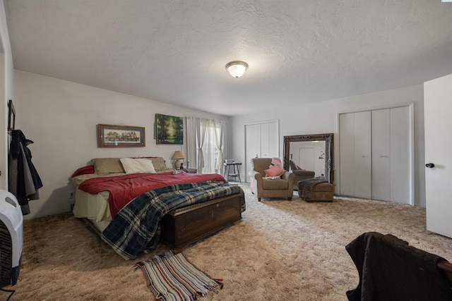 carpeted bedroom featuring a textured ceiling and multiple closets