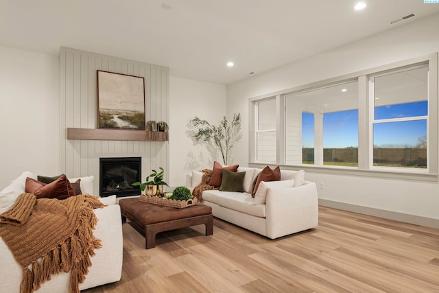 living room featuring light hardwood / wood-style flooring and a large fireplace