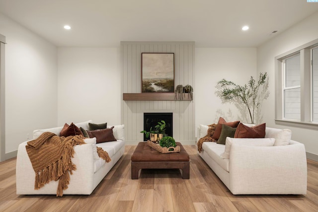 living room with light hardwood / wood-style floors and a large fireplace