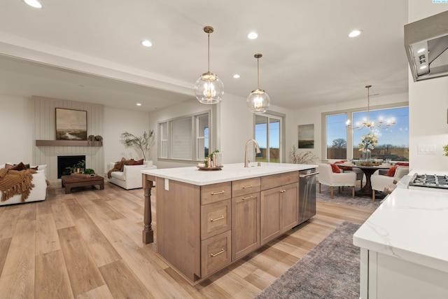 kitchen with a kitchen island with sink, hanging light fixtures, light hardwood / wood-style floors, and appliances with stainless steel finishes