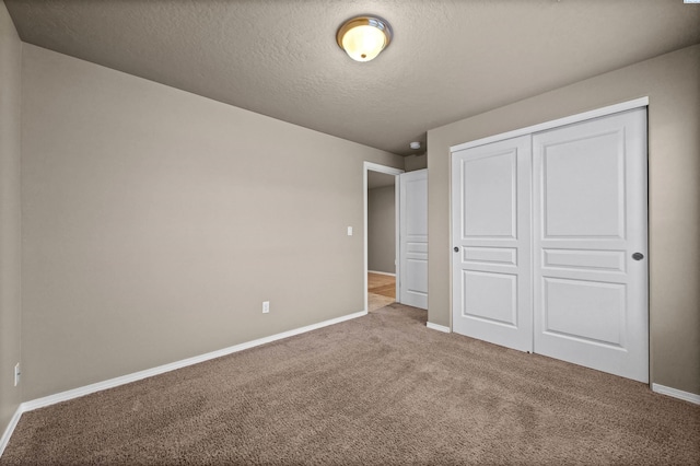 unfurnished bedroom featuring light colored carpet, a textured ceiling, and a closet