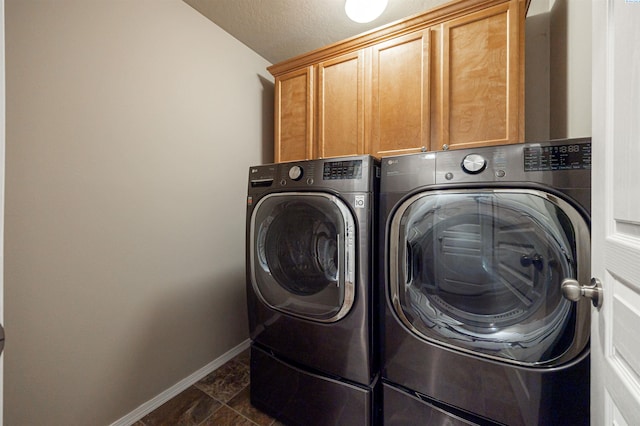 clothes washing area featuring cabinets, a textured ceiling, and washing machine and clothes dryer