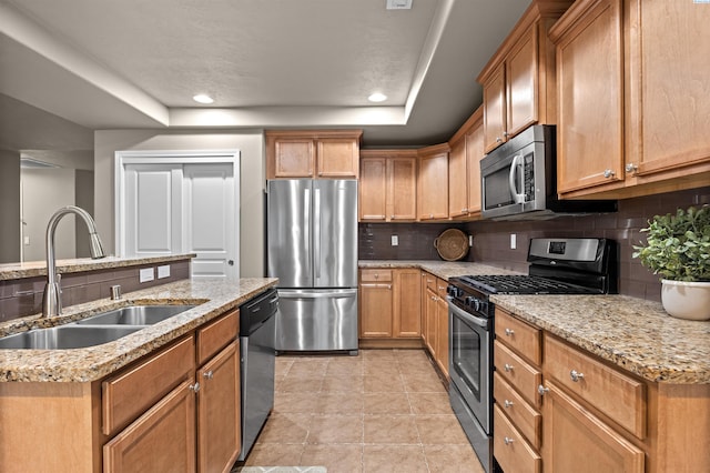 kitchen with tasteful backsplash, a raised ceiling, sink, light stone counters, and stainless steel appliances