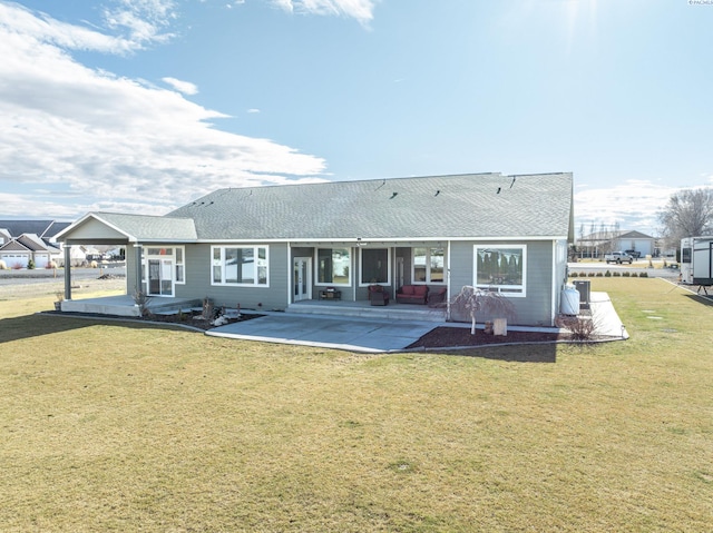 rear view of property with a yard, roof with shingles, and a patio