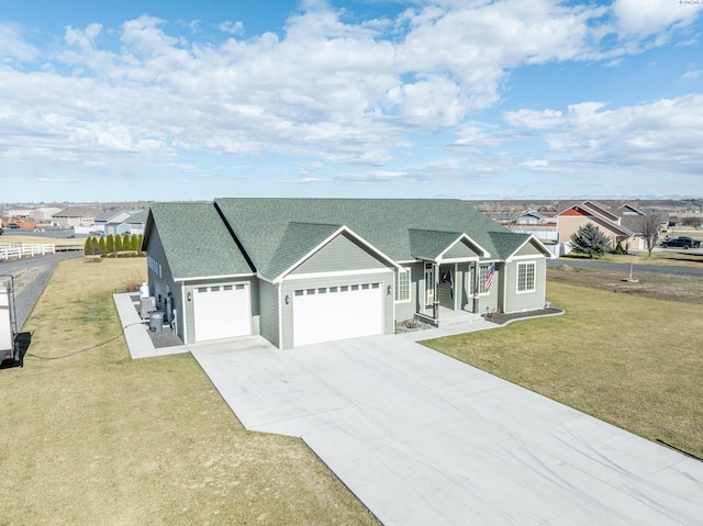 view of front facade with a garage, driveway, a shingled roof, and a front yard