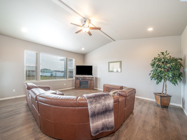 living room featuring lofted ceiling with beams, baseboards, wood finished floors, and a glass covered fireplace