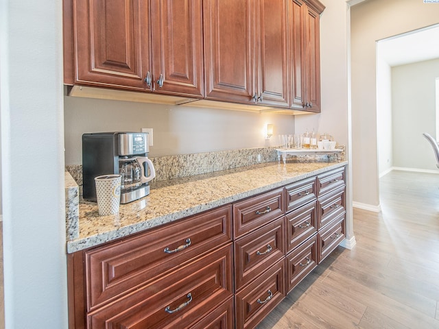 kitchen featuring baseboards, wood finished floors, and light stone countertops