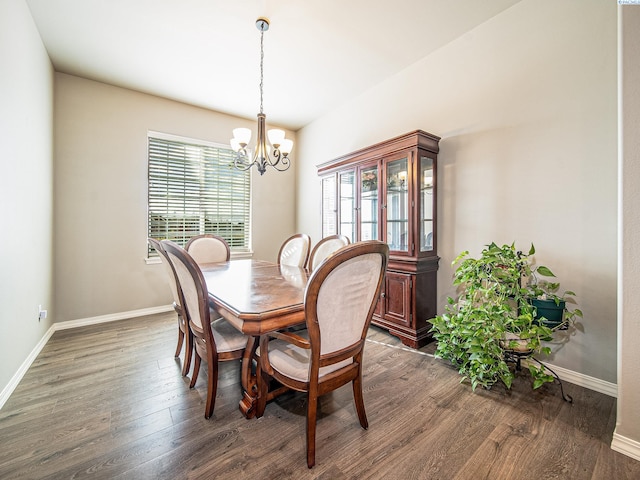 dining space with baseboards, wood finished floors, and an inviting chandelier