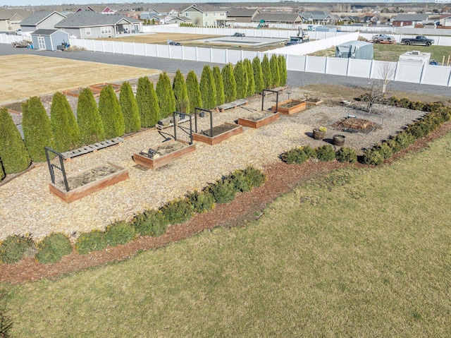 view of yard featuring a garden, a fenced backyard, and a residential view