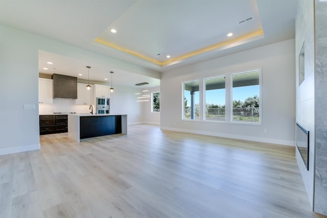 1557 Livorno Ave, Richland, WA 99352 - unfurnished living room featuring a large fireplace, visible vents, a raised ceiling, and light wood finished floors