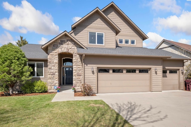craftsman house featuring a front yard, driveway, stone siding, and a shingled roof