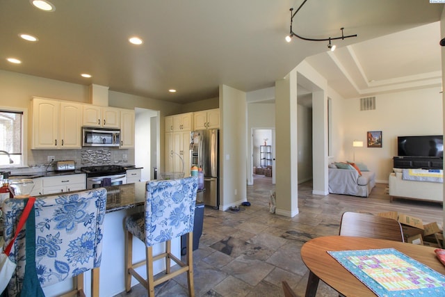 kitchen featuring appliances with stainless steel finishes, tasteful backsplash, sink, a kitchen breakfast bar, and dark stone counters