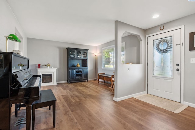 entryway featuring light wood finished floors, baseboards, and a glass covered fireplace