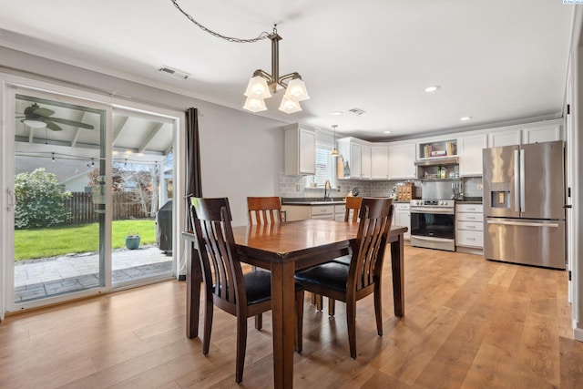dining room featuring a chandelier, light wood finished floors, recessed lighting, and ornamental molding