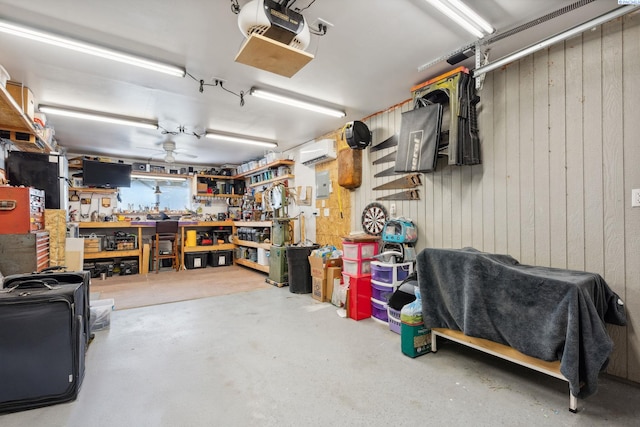 garage with a workshop area, an AC wall unit, a garage door opener, wooden walls, and ceiling fan