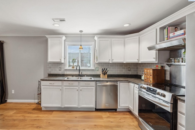 kitchen with appliances with stainless steel finishes, a sink, white cabinets, dark countertops, and under cabinet range hood
