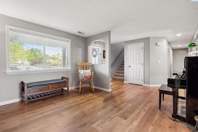 living area with stairway, baseboards, and light wood-style flooring