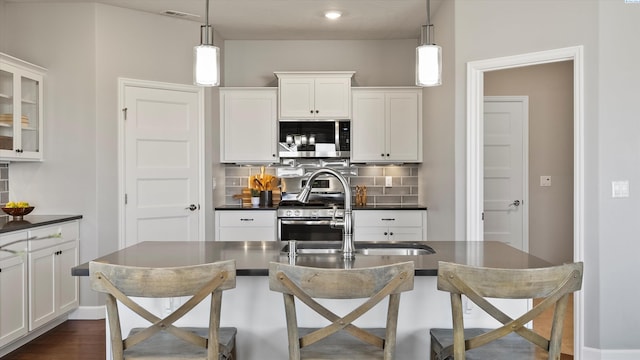 6564 W 38th Ave, Kennewick, WA 99338 - kitchen featuring appliances with stainless steel finishes, dark countertops, decorative backsplash, white cabinetry, and recessed lighting