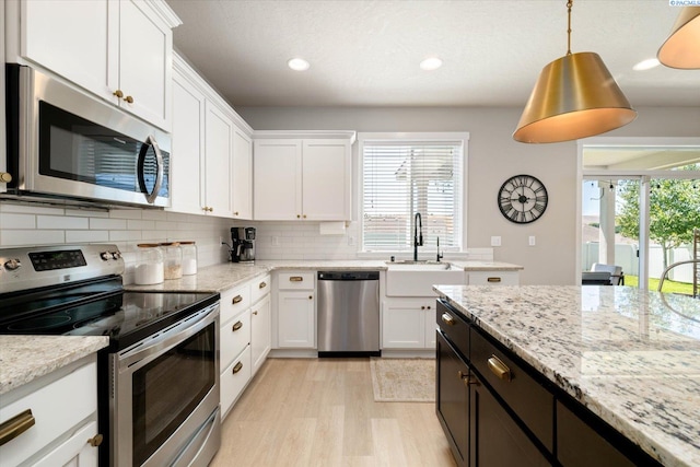 10389 W 17th Pl, Kennewick, WA 99338 - kitchen featuring appliances with stainless steel finishes, white cabinetry, light wood-type flooring, tasteful backsplash, and recessed lighting