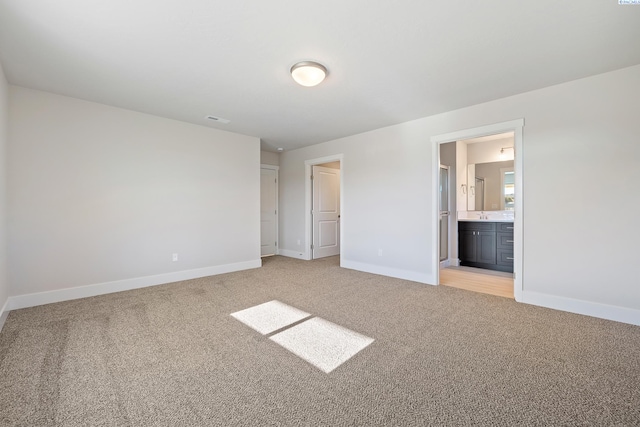 unfurnished bedroom with light colored carpet and ensuite bathroom