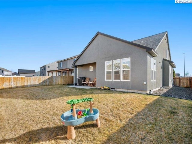 rear view of property with a patio, a yard, a fenced backyard, and stucco siding