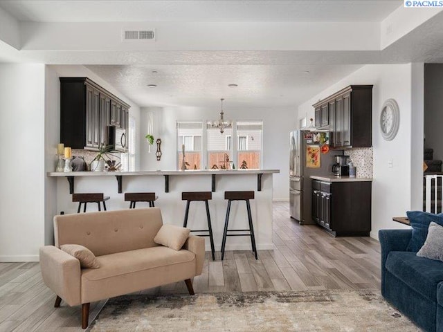 kitchen with light wood-style flooring, a breakfast bar area, open floor plan, and decorative backsplash