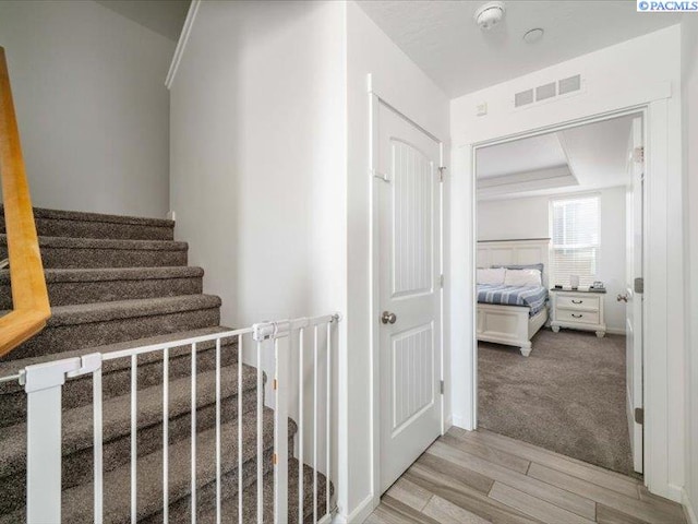 stairs with visible vents and wood finished floors