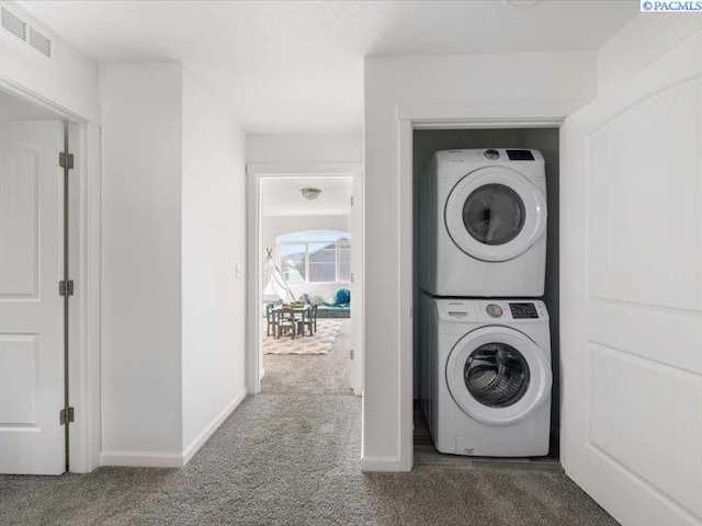 washroom featuring carpet floors, visible vents, stacked washing maching and dryer, laundry area, and baseboards