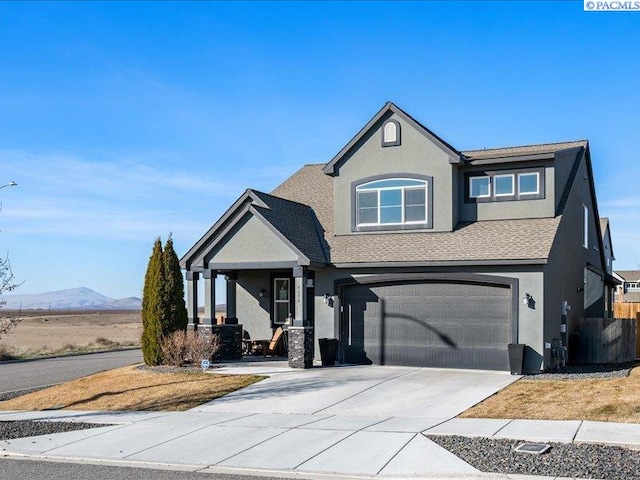 view of front facade featuring stucco siding, a mountain view, fence, a garage, and driveway