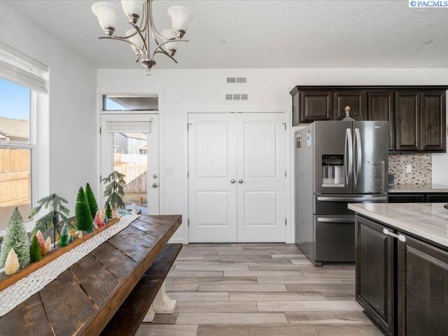 kitchen featuring plenty of natural light, dark brown cabinets, light wood finished floors, and stainless steel refrigerator with ice dispenser