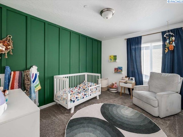 carpeted bedroom featuring a crib, a decorative wall, and a textured ceiling