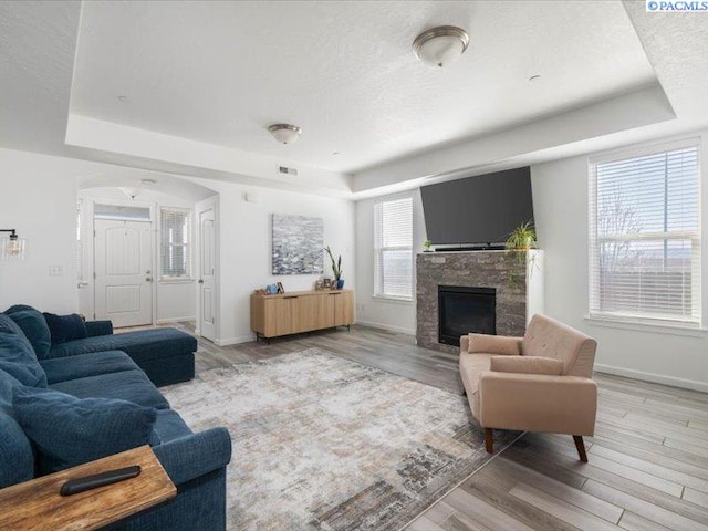 living area featuring light wood-type flooring, baseboards, and a raised ceiling