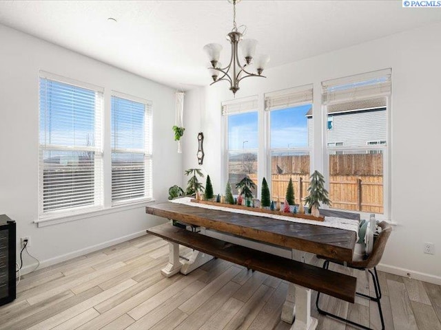 dining space with baseboards, light wood finished floors, and an inviting chandelier