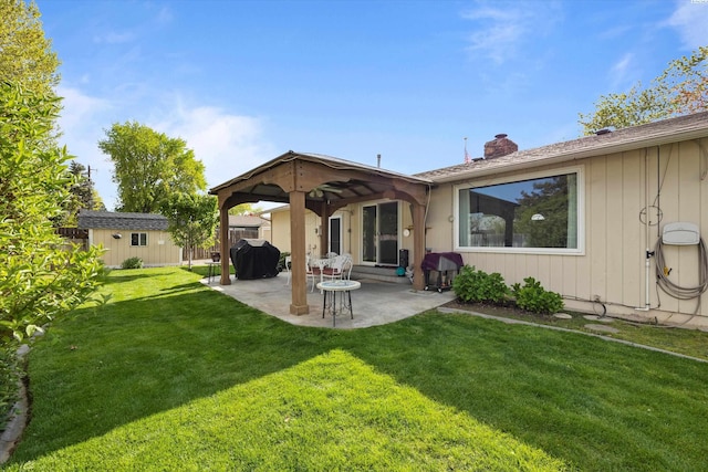 rear view of property featuring a yard, a chimney, a patio area, and an outdoor structure