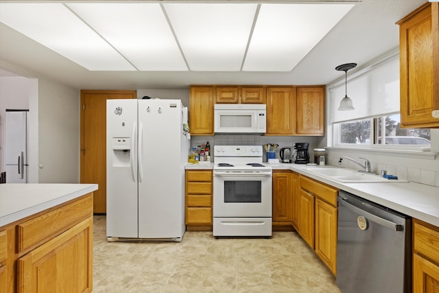 kitchen with pendant lighting, white appliances, sink, and tasteful backsplash