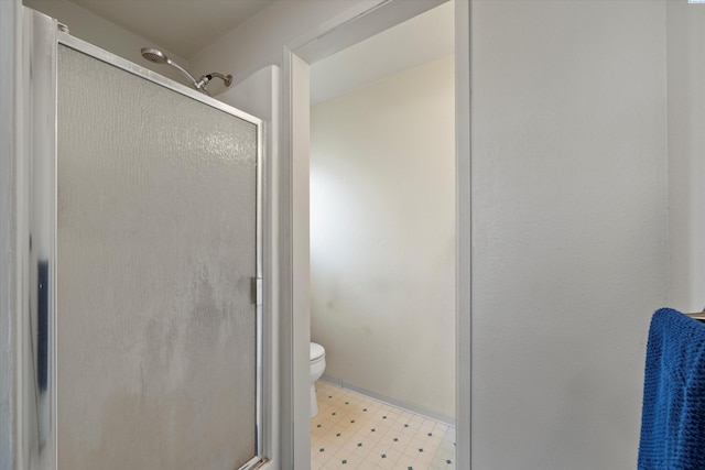 bathroom featuring toilet, tile patterned floors, and a stall shower