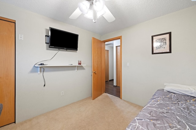 carpeted bedroom with ceiling fan and a textured ceiling