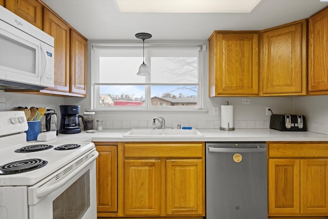 kitchen with sink, white appliances, and decorative light fixtures