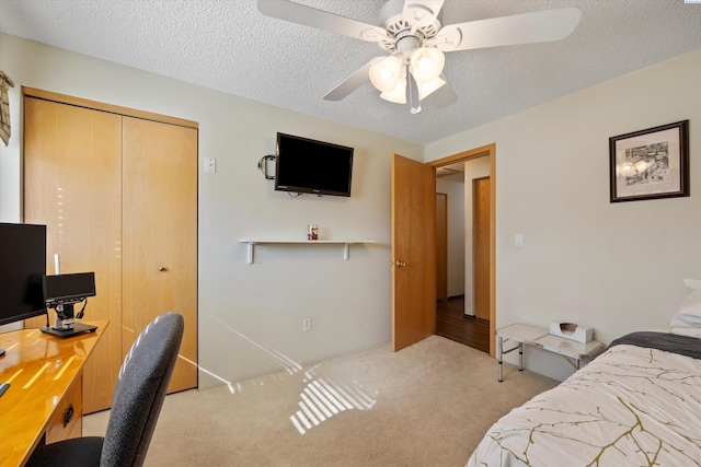 bedroom with light colored carpet, a ceiling fan, a textured ceiling, and a closet